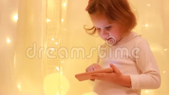 女孩看着智能手机屏幕在下载的应用程序中播放视频的预览图