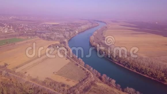 无人驾驶飞机缓慢地飞越蓝河和农田视频的预览图
