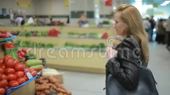 一个女人在超市的蔬菜货架上买蔬菜和水果视频的预览图