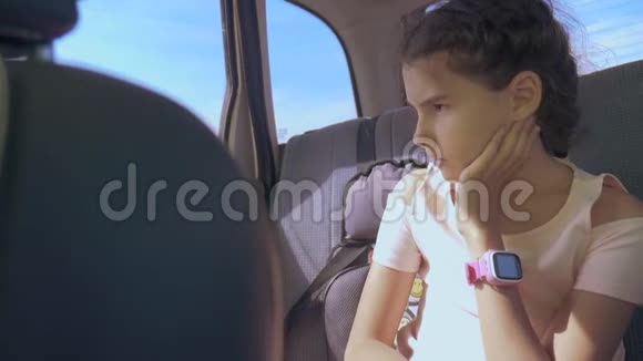 伤心的女孩无聊地坐在汽车后座旅行小女孩在车里感到无聊长途运动视频的预览图