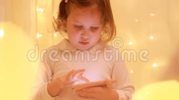 小女孩看着智能手机屏幕在下载的应用程序中播放视频的预览图