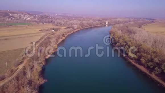 无人驾驶飞机缓慢地飞越蓝河和农田视频的预览图