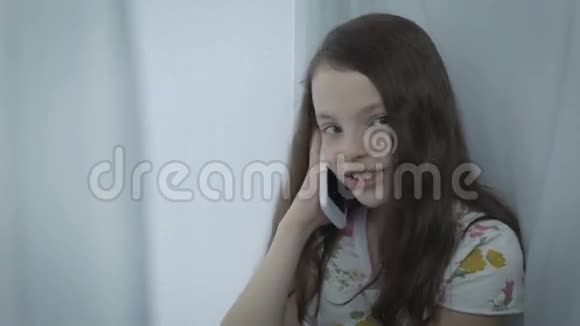 漂亮的小女孩在智能手机上情绪化说话视频的预览图