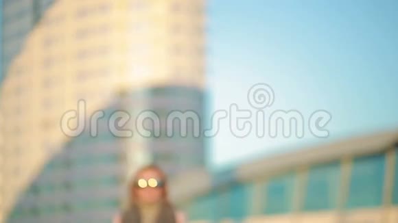 穿着粉红色外套的女孩走在摩天大楼背景下的现代城市视频的预览图