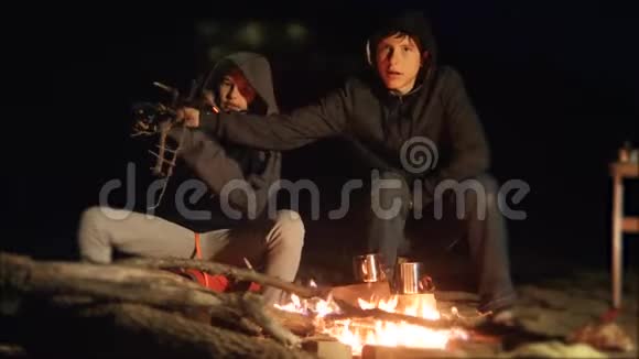 孩子们微笑孩子们喝茶青少年坐在篝火旁旅行徒步旅行冒险野营冒险视频的预览图