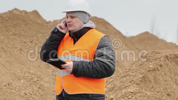 土木工程师在一堆沙子上用手机说话视频的预览图