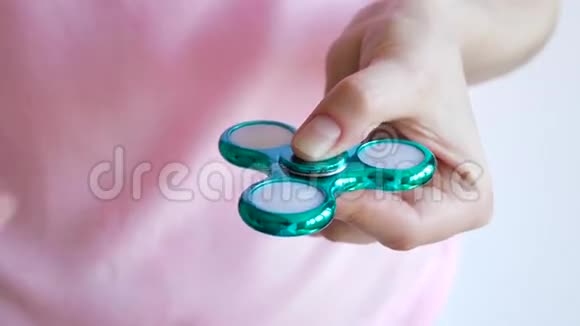 女孩玩着一个光滑明亮色彩鲜艳的手烦躁的旋转玩具视频的预览图