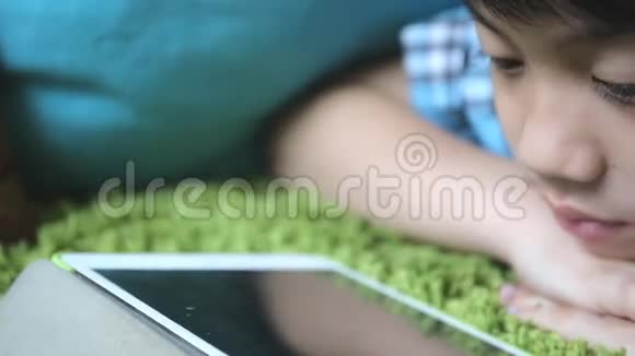 小亚洲小孩微笑着在脸上玩平板电脑视频的预览图