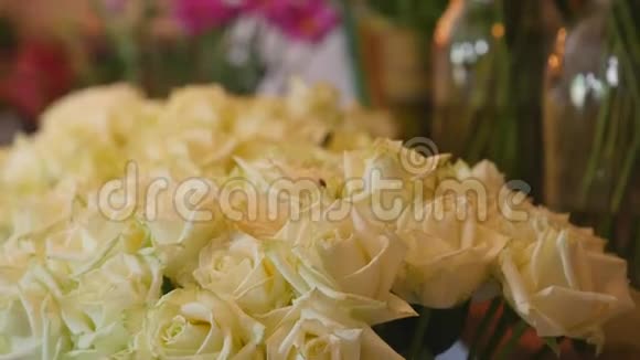 在花店里用一束束绿色的茎叶组成的白色鲜玫瑰特写镜头出售视频的预览图