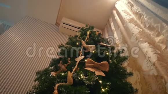 美丽的金发女孩在舒适的晚屋里装扮一棵圣诞树视频的预览图