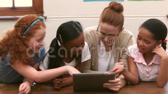 微笑老师和学生在教室里使用平板电脑视频的预览图