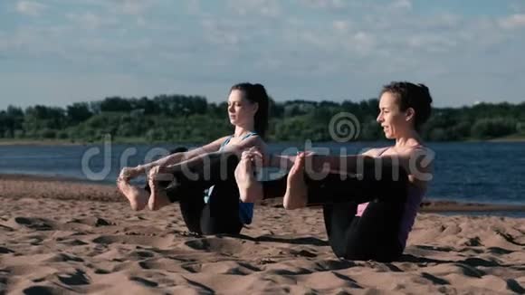 两个女人在城市河边的海滩上做瑜伽城市美景视频的预览图