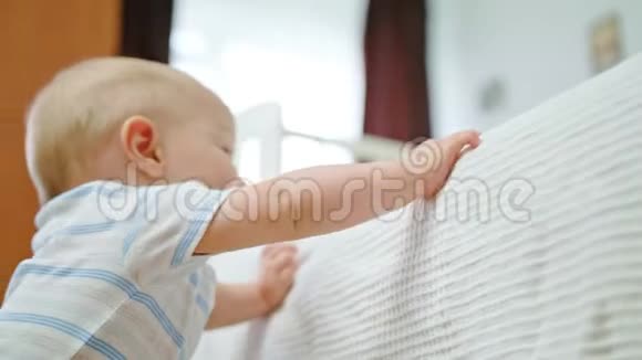可爱的宝宝在家里的婴儿床上玩耍视频的预览图