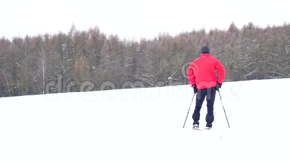 冬季游客带着雪鞋在雪地漂流中行走穿着粉色运动夹克的徒步旅行者和穿着雪鞋的黑色徒步旅行者视频的预览图