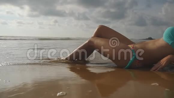 美丽的年轻女子躺在沙滩上的金色沙滩上在暑假旅行中放松海洋海浪视频的预览图
