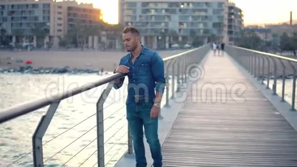 一个年轻英俊的男人在美丽的海滩附近的桥上视频的预览图