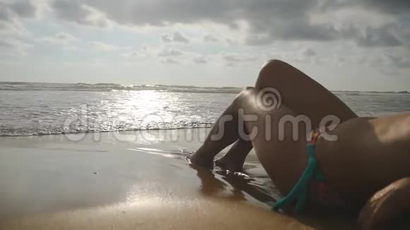 美丽的年轻女子躺在沙滩上的金色沙滩上在暑假旅行中放松海洋海浪视频的预览图