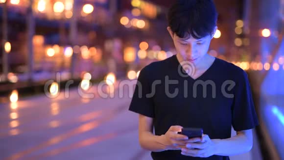 亚洲男子夜间使用手机户外活动画像视频的预览图