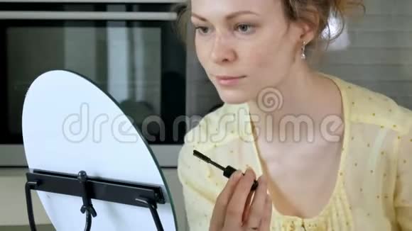 年轻漂亮的女人在家里对着镜子化妆视频的预览图