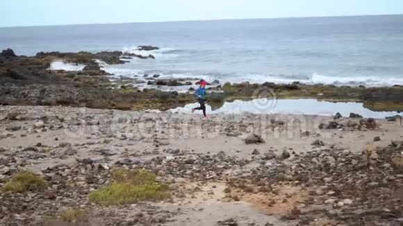 女人沿着海洋的石岸奔跑健康的生活方式视频的预览图