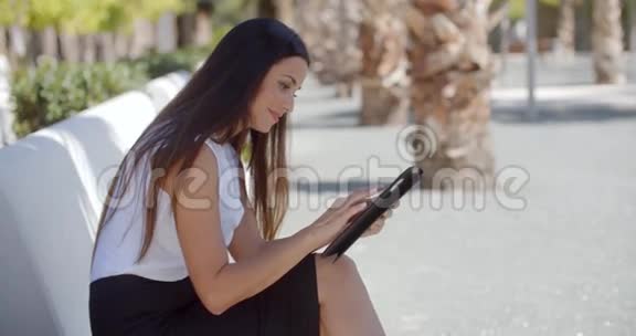 在户外使用平板电脑的年轻女子微笑视频的预览图
