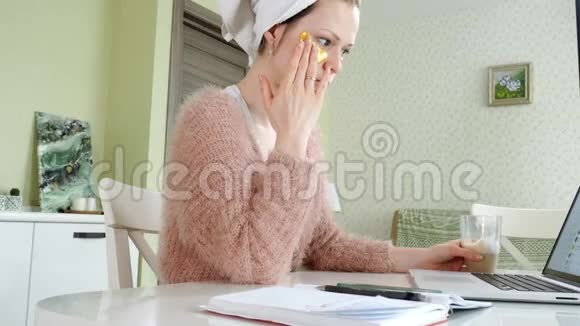 有魅力的女商人在家里涂化妆品在笔记本电脑后面工作视频的预览图