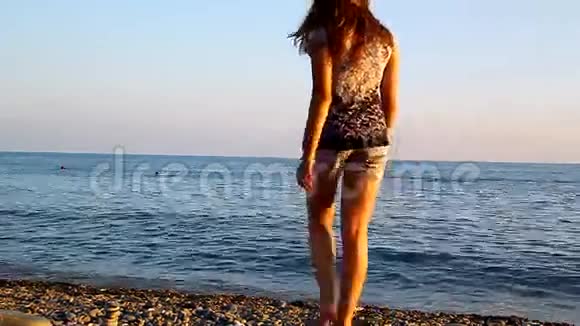 年轻漂亮的女孩在海滩上散步视频的预览图