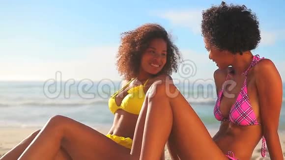 快乐的黑发女人坐在沙滩上视频的预览图