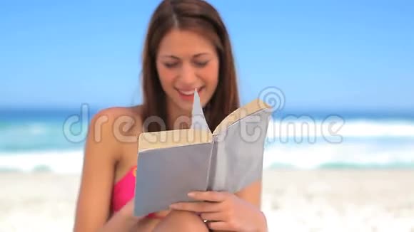 微笑的黑发女人在读一本有趣的小说视频的预览图