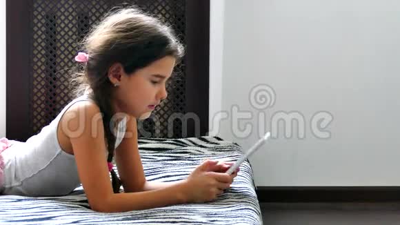 坐在床上玩平板电脑网络游戏的少女视频的预览图