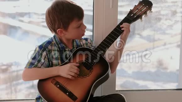 演奏乐器男孩坐在窗台上弹吉他视频的预览图