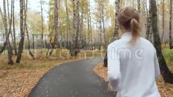 年轻的金发女人在秋天公园跑步视频的预览图