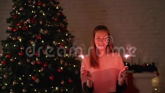 一个女孩拿着孟加拉灯对着圣诞树视频的预览图