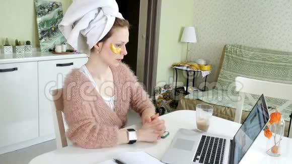 有魅力的女商人在家里涂化妆品在笔记本电脑后面工作视频的预览图