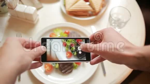 餐馆里的时髦男人用手机相机拍食物视频的预览图