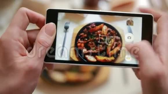 餐馆里的时髦男人用手机相机拍食物视频的预览图
