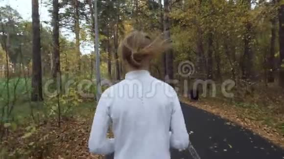 年轻的金发女人在秋天公园跑步视频的预览图