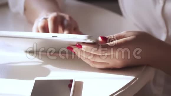那个女人在一张白色的桌子上做红色的指甲漂亮的轻便桌面那个女人在平板电脑上工作这就是视频的预览图