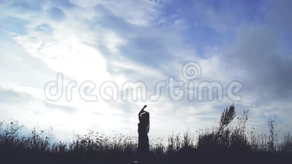一个女孩在背景上美丽的天空的剪影视频的预览图