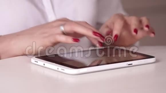 那个女人在一张白色的桌子上做红色的指甲漂亮的轻便桌面那个女人在平板电脑上工作这就是视频的预览图