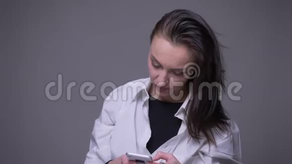 使用电话和微笑的白种人成年女性的特写肖像背景与灰色隔离视频的预览图