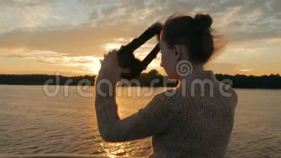 日落时分在游轮甲板上戴虚拟现实眼镜的女人视频的预览图