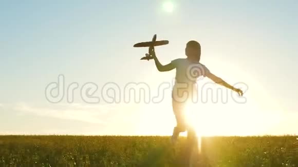 快乐的女孩带着玩具飞机在夕阳下的田野上奔跑孩子们玩玩具飞机青少年的梦想视频的预览图