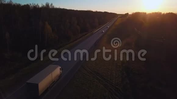 空中带着集装箱的汽车在通往日落的道路上行驶卡车在高速公路上行驶视频的预览图