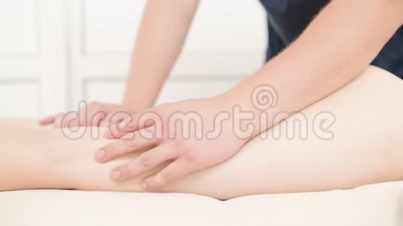 一位男性理疗师做一次轻按摩以暖和一位年轻女性的臀部和臀部视频的预览图