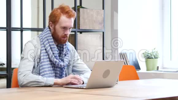 胡子男在手提电脑工作时庆祝成功视频的预览图