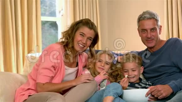 微笑的家人看电视吃爆米花视频的预览图