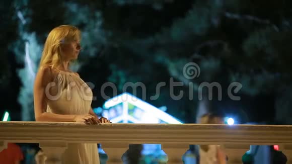 穿着白色长裙的女孩晚上沿着海滩散步视频的预览图