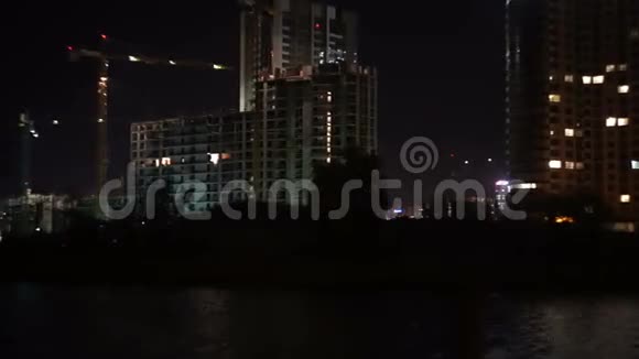 正在建造中的建筑物夜间从河中眺望视频的预览图