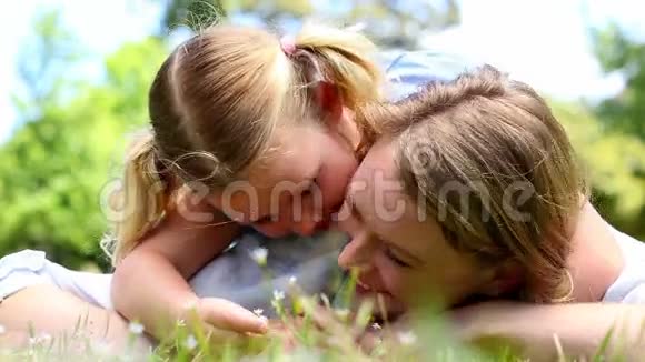 快乐的母亲和她的小女孩躺在草地上公园里视频的预览图